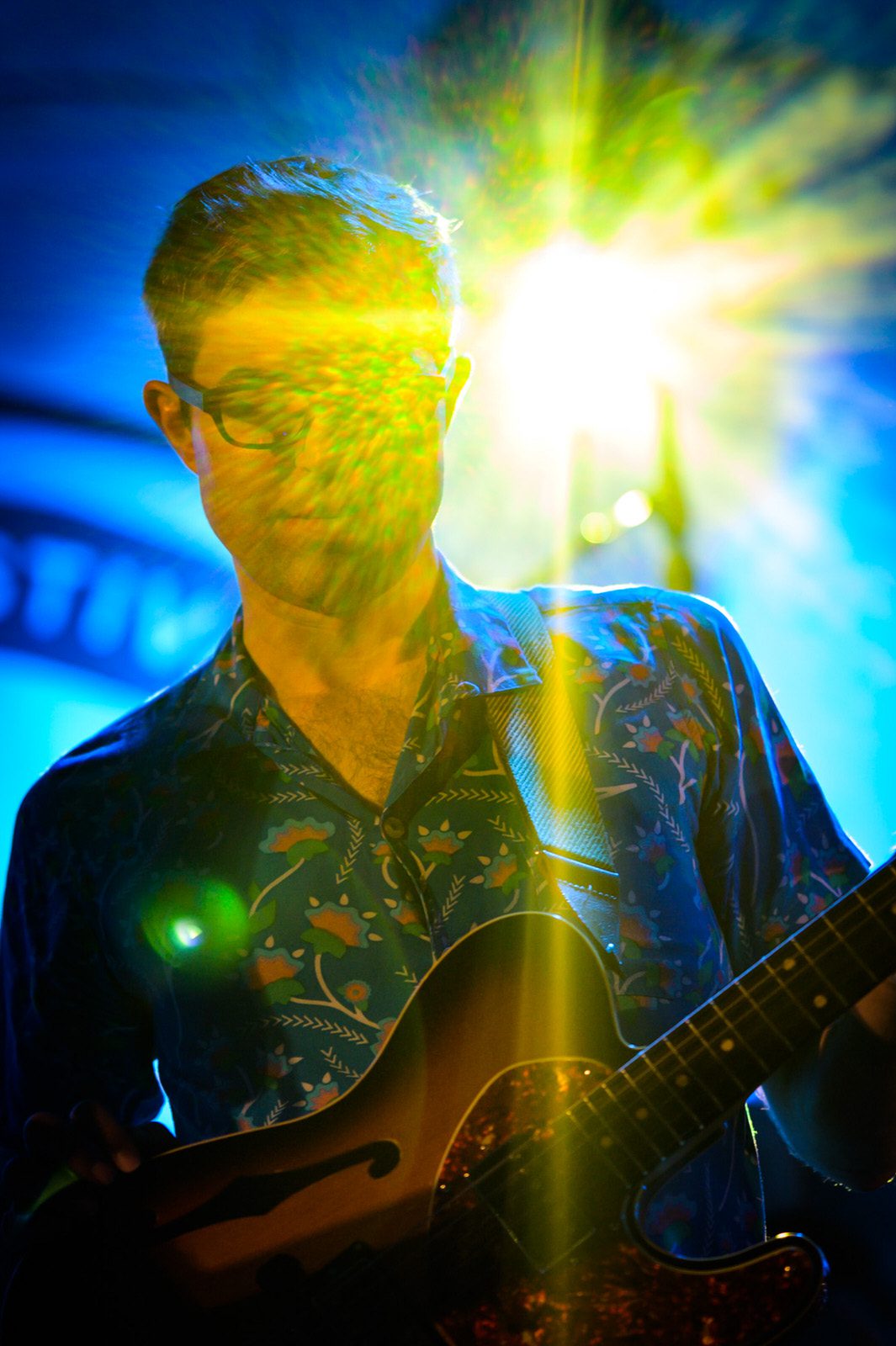 Guitarist Chris McQueen playing with Snarky Puppy on stage with bright lights