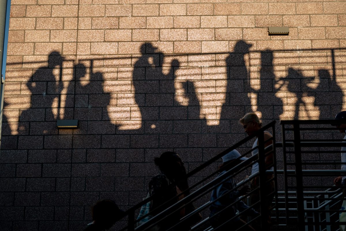 Shadows of fans cast against a stadium wall in late light at the 2025 US Open, abstract storytelling frame.