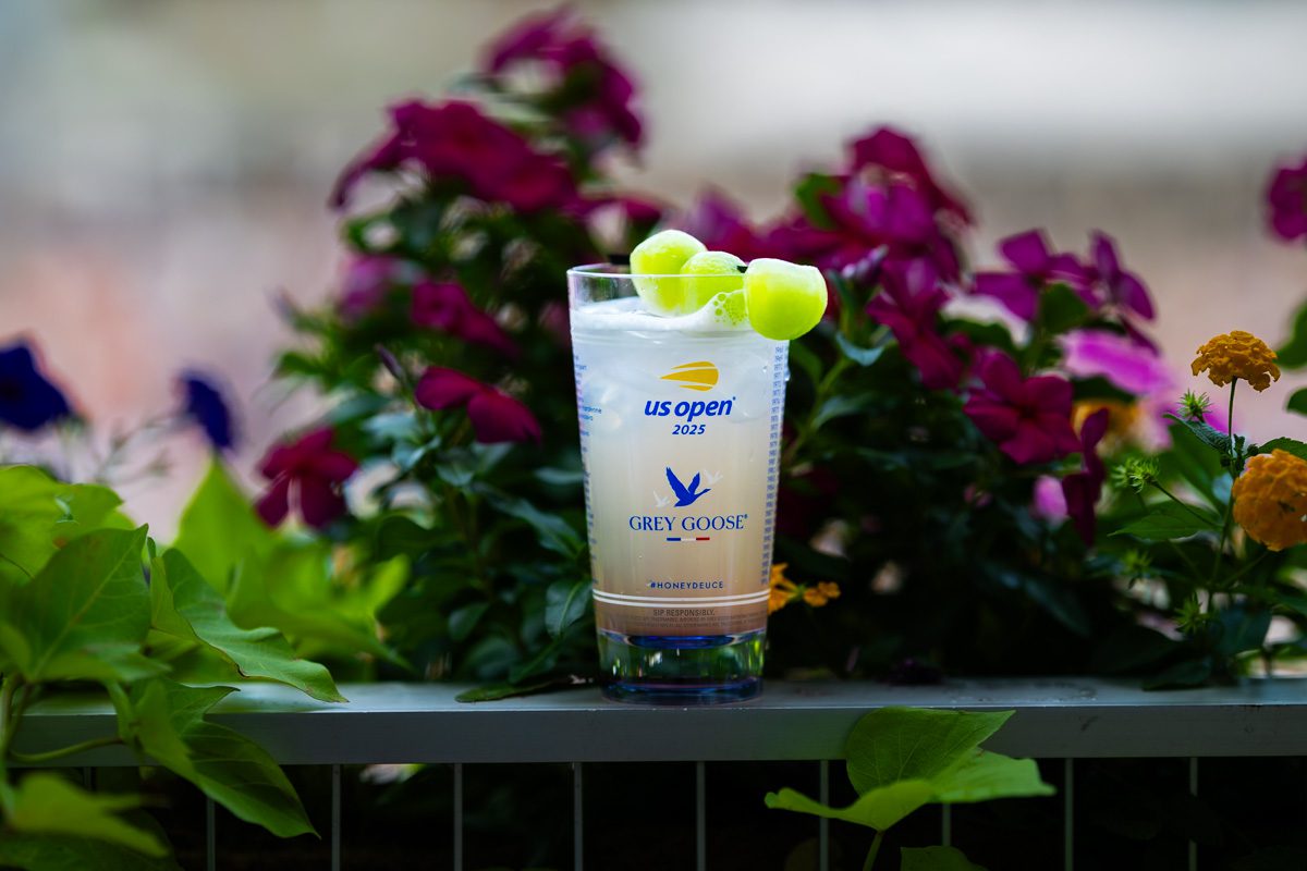 Iconic Grey Goose Honey Deuce cocktail with melon garnish, photographed at the 2025 US Open in floral setting.