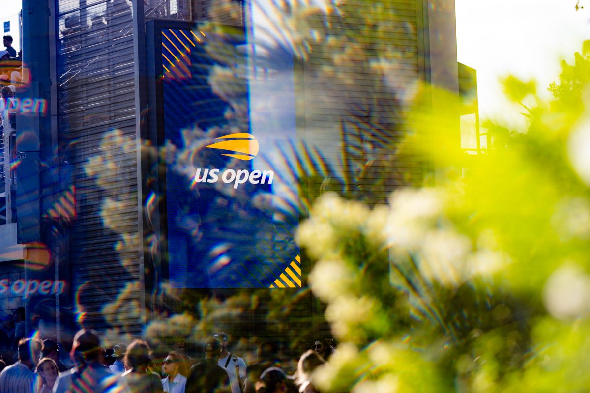 US Open digital signage refracted through prism and foliage, creating layered rainbow effect.