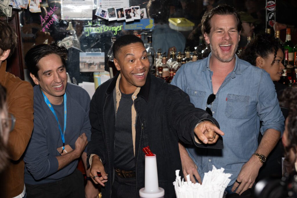 Two men react with big smiles as one points toward the crowd inside Pioneer Saloon during the Fallout celebration.