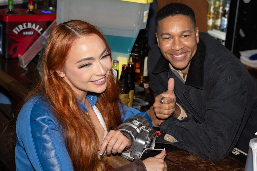 A woman and a man laugh together at the bar during the Fallout fan celebration.