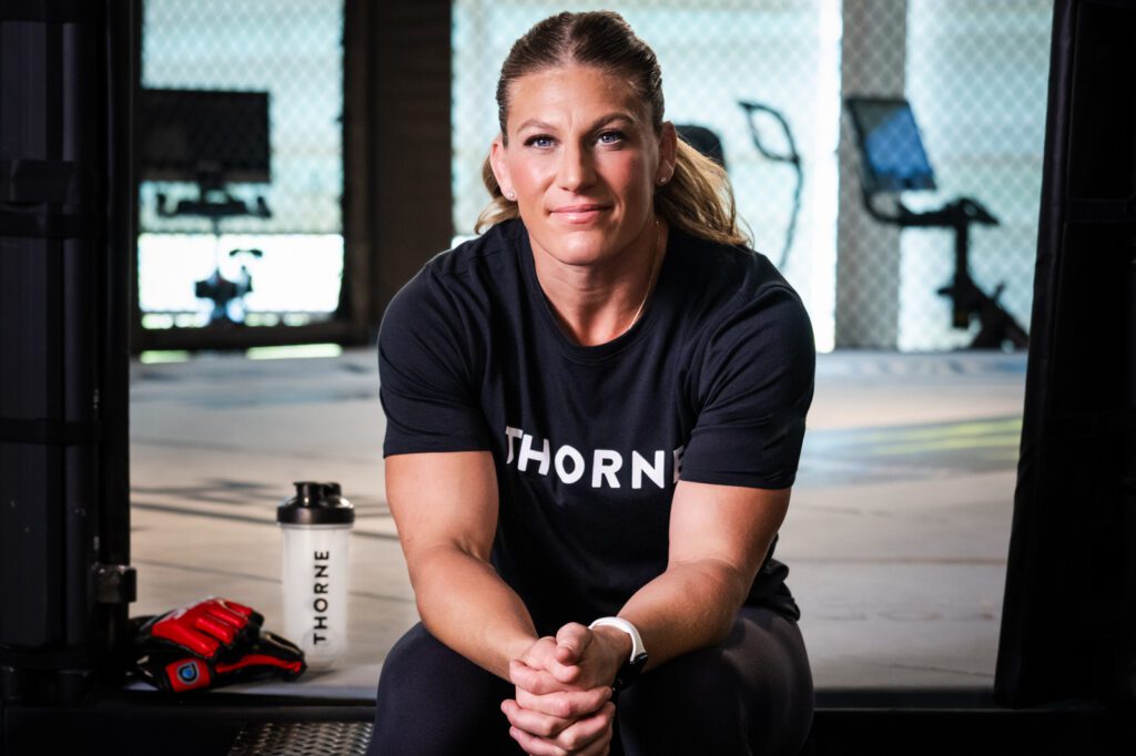 Kayla Harrison seated on the mat inside the UFC Performance Institute during a Thorne campaign photo shoot in Las Vegas.