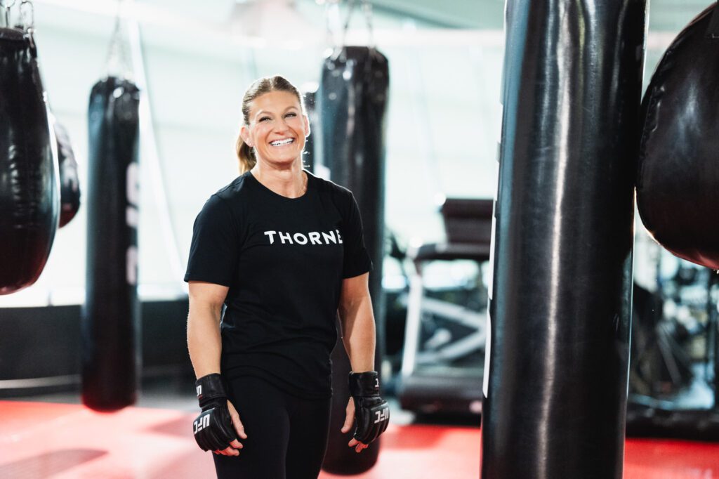Kayla Harrison smiling between training sets during a Thorne supplements campaign shoot at the UFC Performance Institute in Las Vegas.