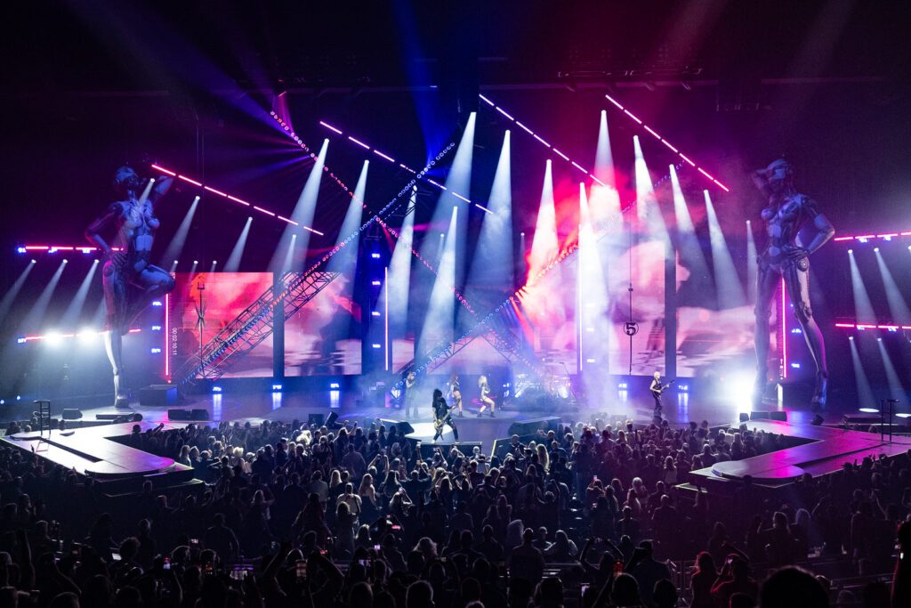 Full-room image showing Mötley Crüe’s Dolby Live stage exploding in magenta and white beams, fans filling the floor and the scale of PRG’s production lighting.
