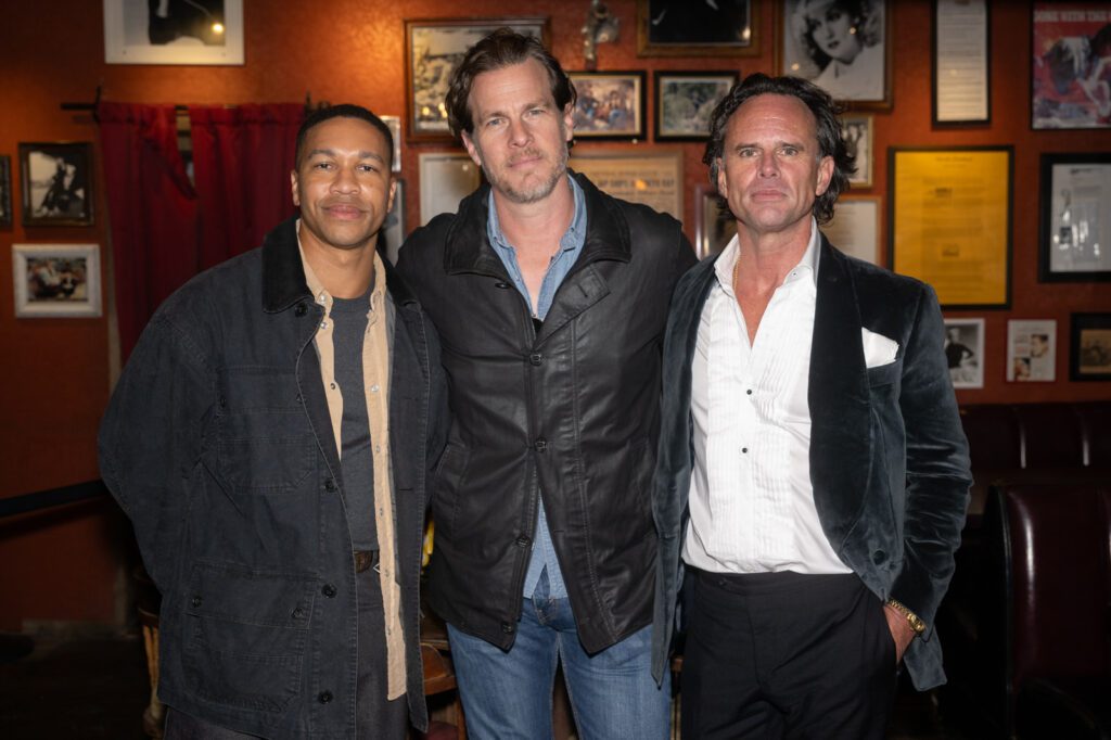 Three men stand together for a group photo inside Pioneer Saloon during the Fallout fan event.