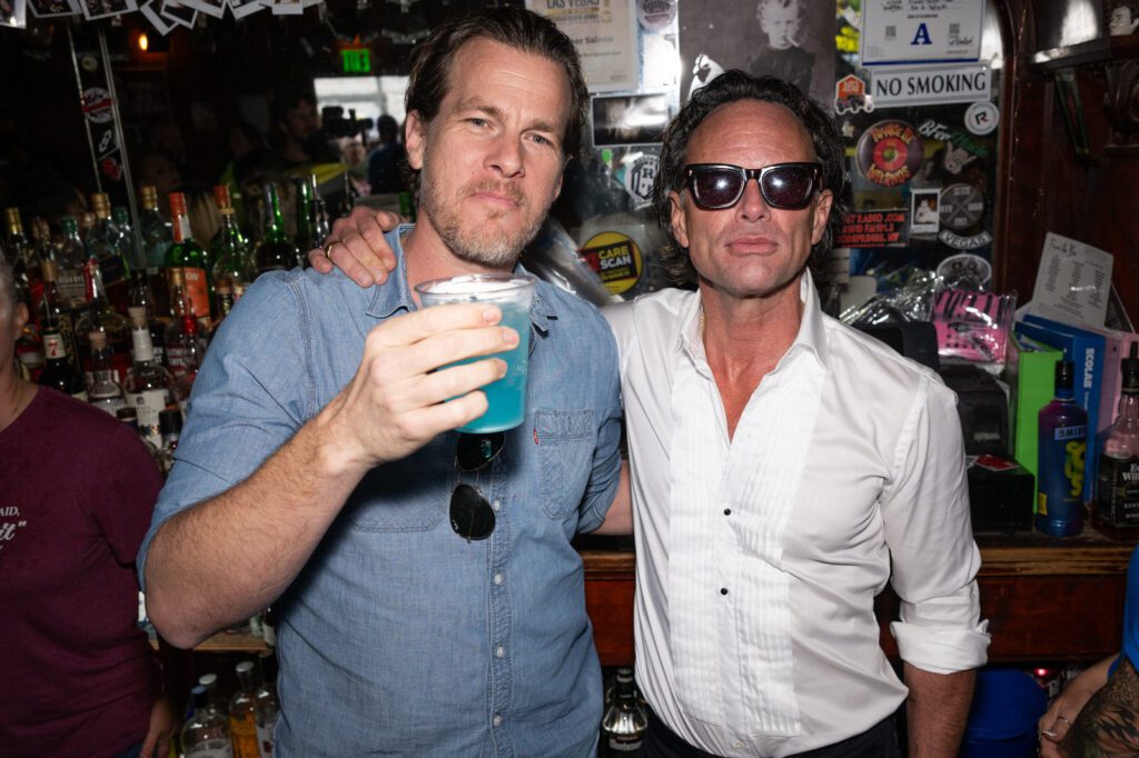 Two men pose together with drinks inside Pioneer Saloon during the Fallout fan celebration.