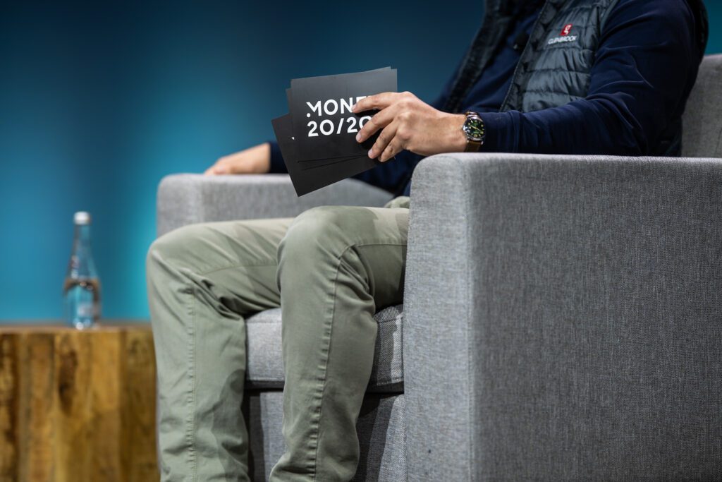 Detail view of a speaker seated on stage during a Convera booth session at Money20/20