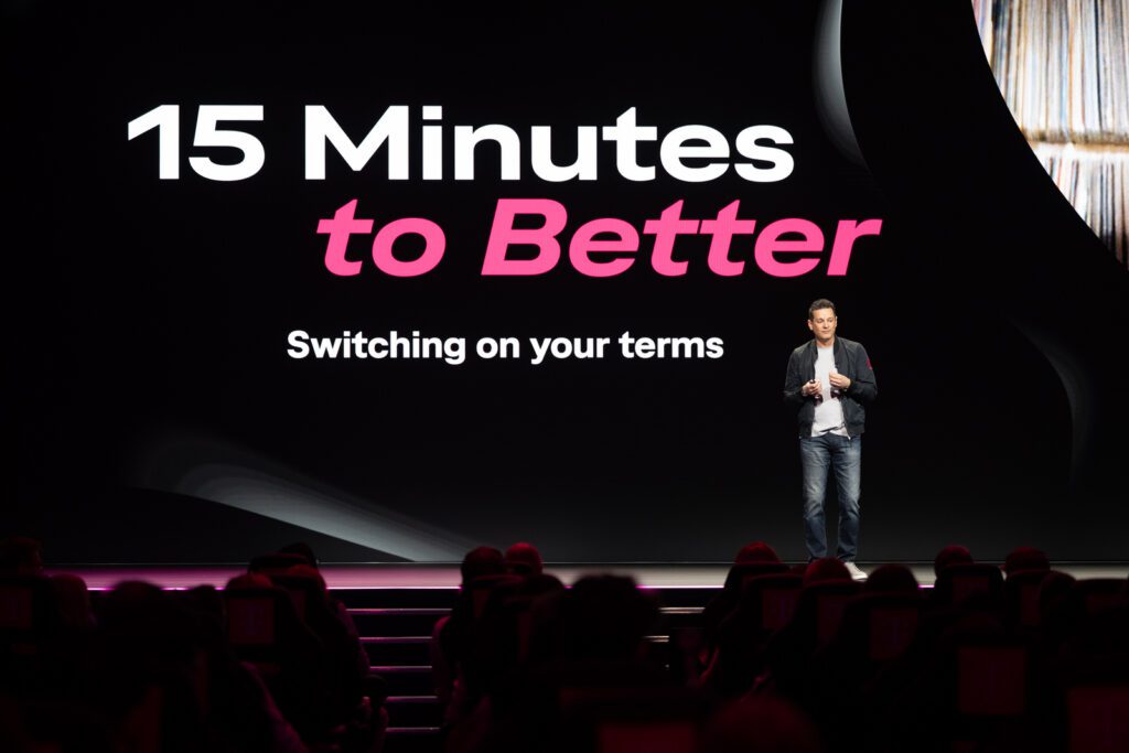 Stage moment from T-Mobile’s Switching Made Easy announcement, showing the “15 Minutes to Better” message during the keynote presentation.