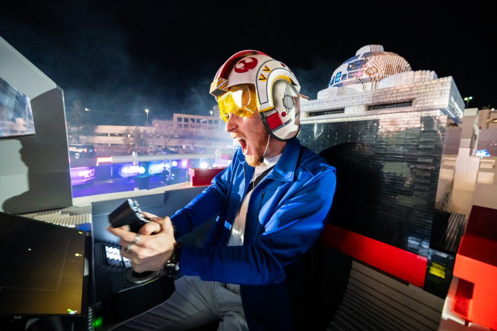 Guest wearing a pilot helmet inside the LEGO Star Wars X-wing cockpit during the SMART Play activation at Sphere Las Vegas