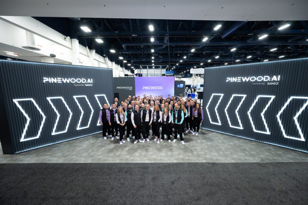Full Pinewood.AI team photo in matching uniforms in front of branded walls at NADA 2026 Las Vegas