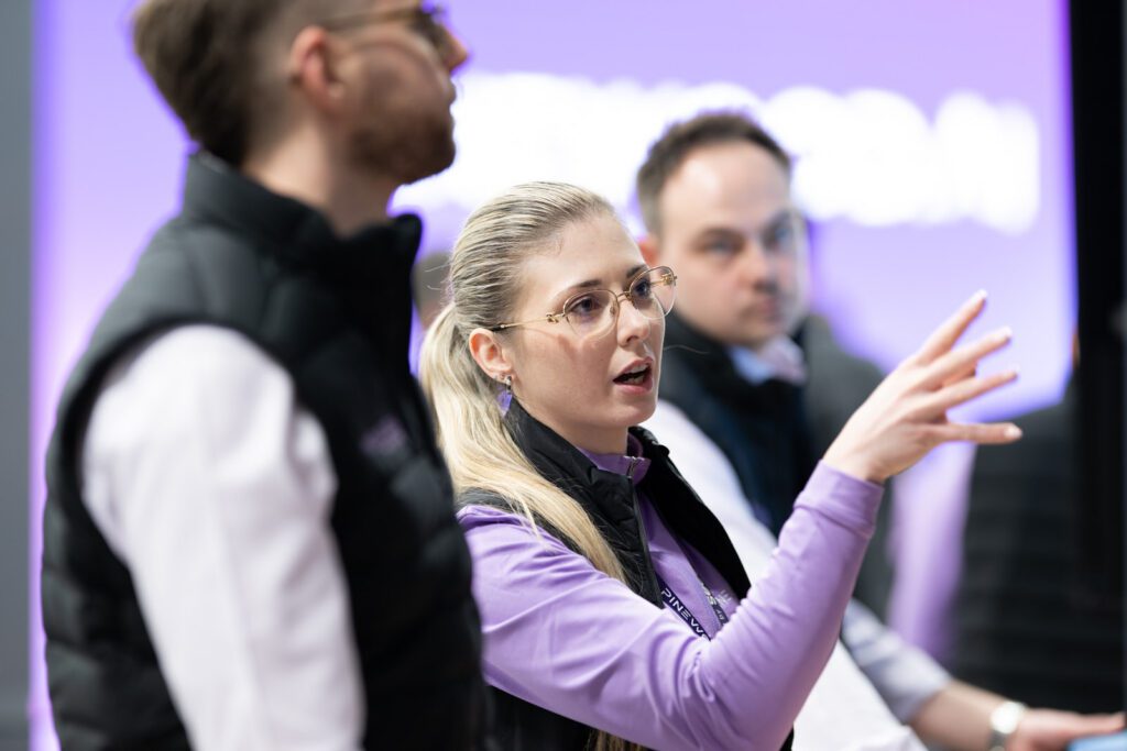 Pinewood.AI team member in conversation with an attendee at NADA 2026 — Las Vegas corporate event photographer B-Freed